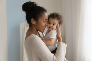 Smiling mother holding and snuggling baby